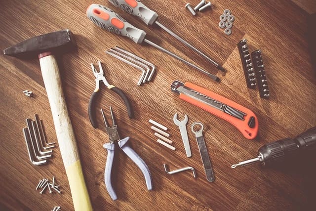 Reparaturwerkzeuge wie Schraubenzieher, Zangen und Schraubenschlüssel für Reparaturen im Reparatur Café, symbolisiert durch Werkzeuge auf einem Holztisch.